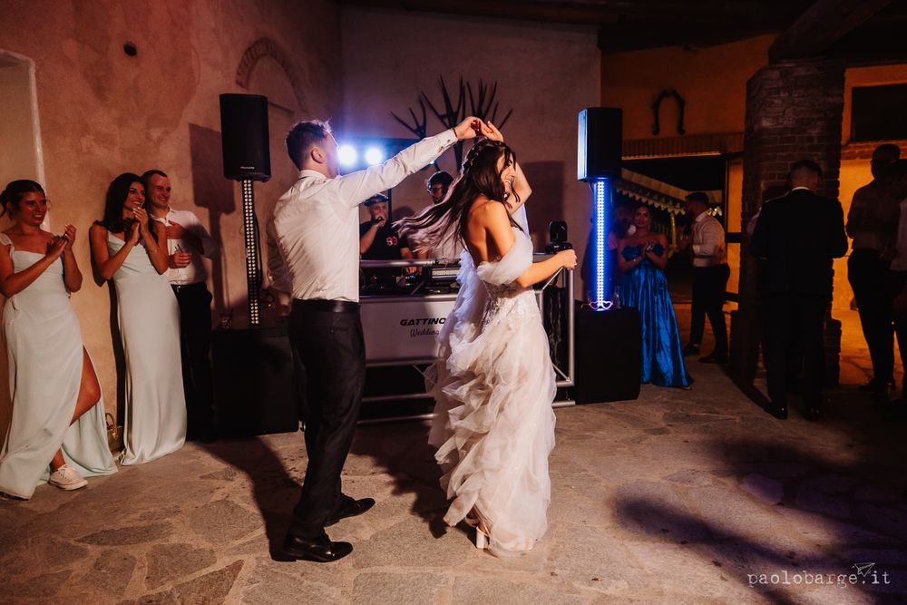 Wedding couple dancing energetically in a rustic venue with mood lighting.