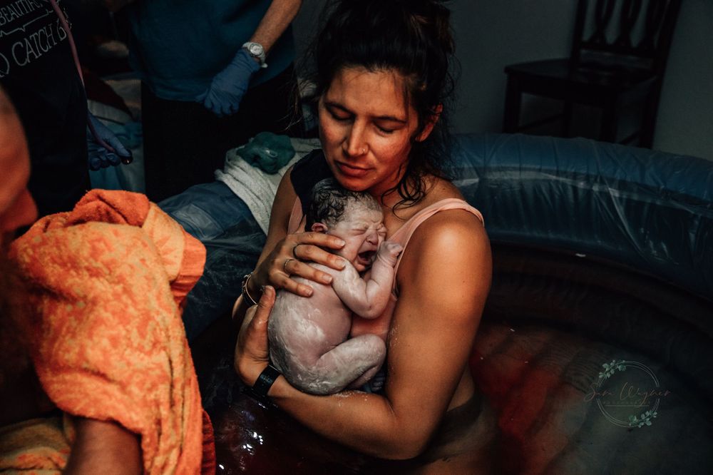 NWA mom holds her baby in a pool at home after giving birth
