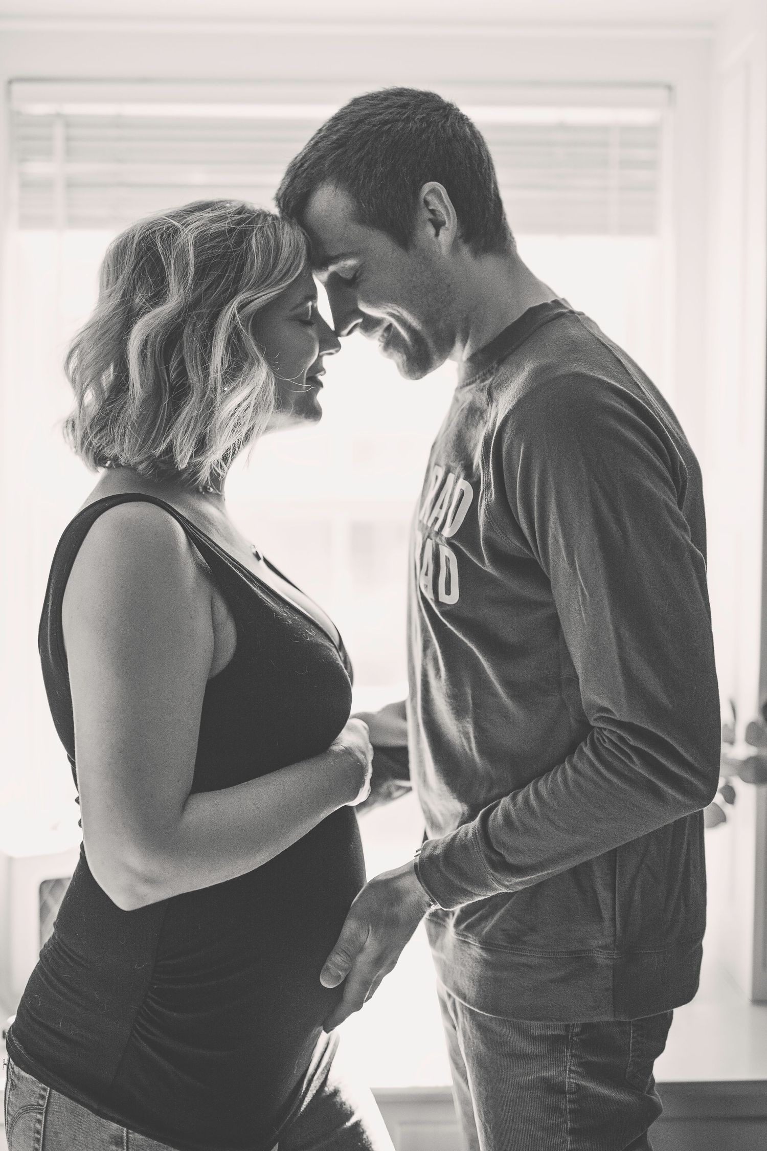 Intimate black and white portrait of couple sharing tender moment indoors.