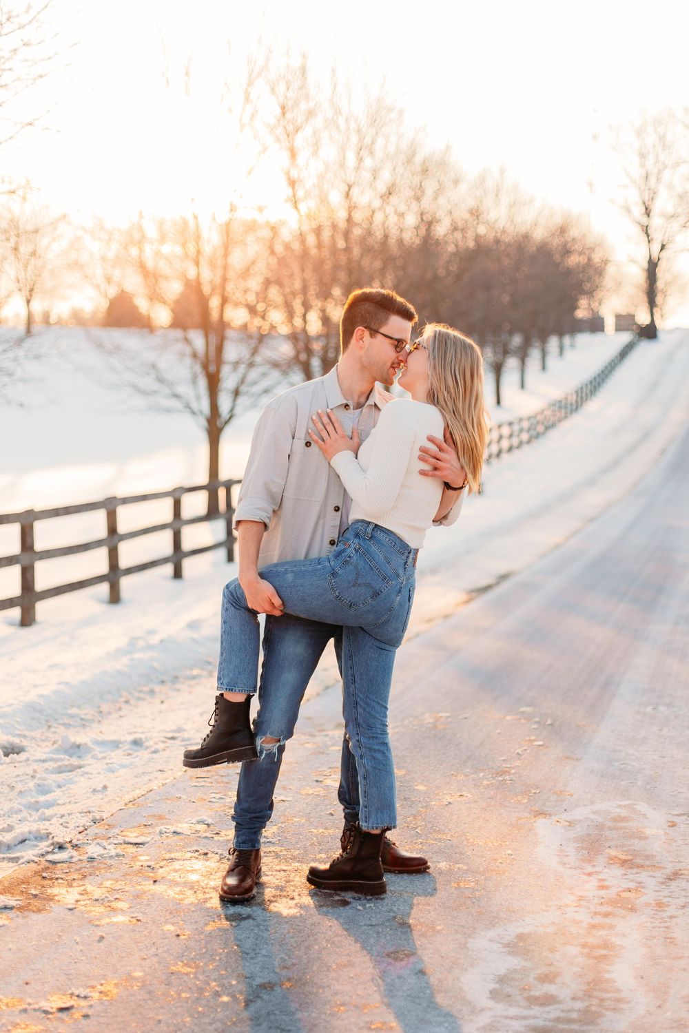 A winter engagement session with a snowy sunset and a rustic fence. Couples photography inspiration