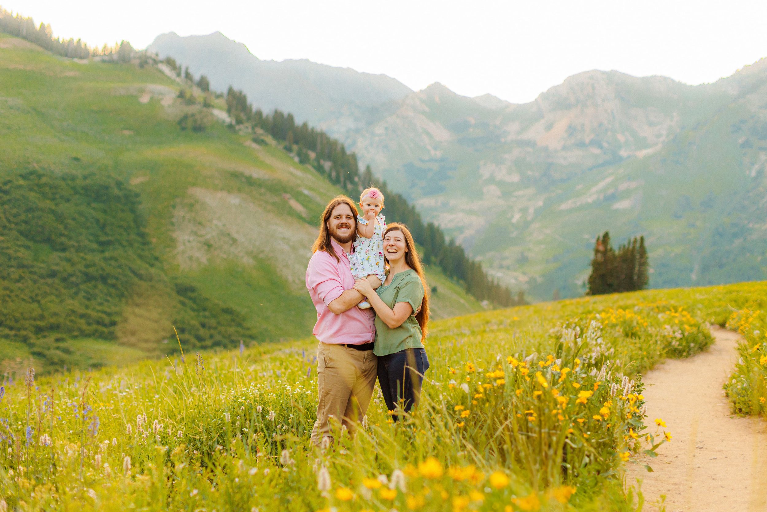 People enjoying a sunny day on a mountain hiking trail surrounded by alpine wildflowers in Alta, Utah.