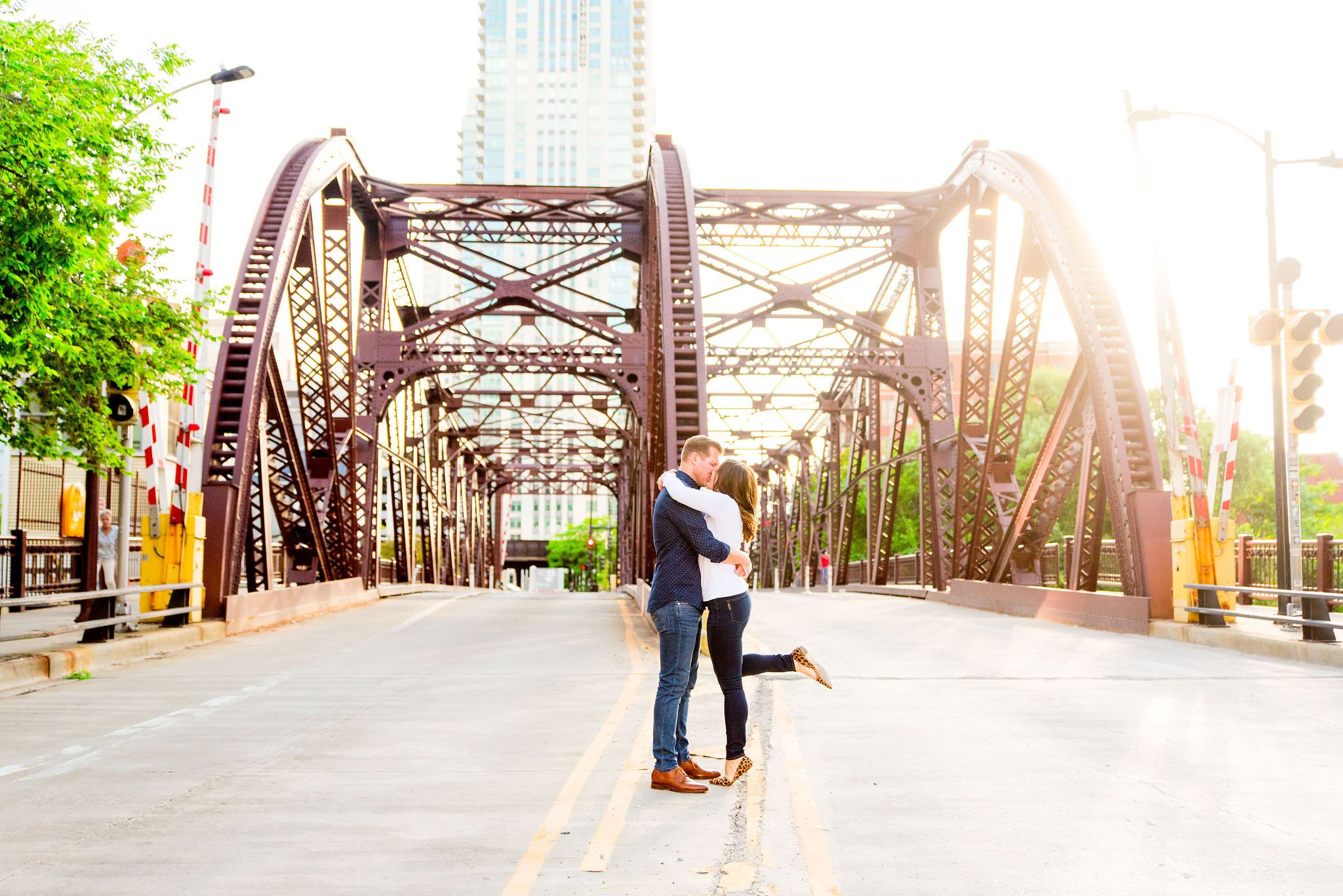 man and woman kissing in front of Kinzie St Bridge with her one leg up in leopard flat
