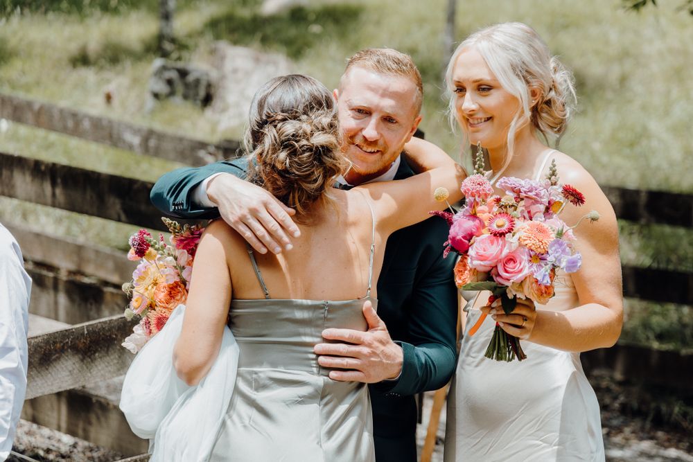 Emotional moment shared between wedding party members during outdoor celebration.