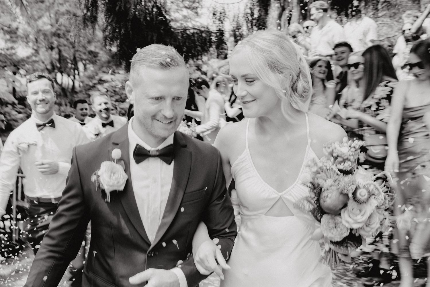 Black and white photo captures newlyweds' joy during wedding recessional.