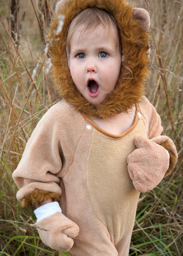 girl in lion costume roaring in field of dry tall grasses