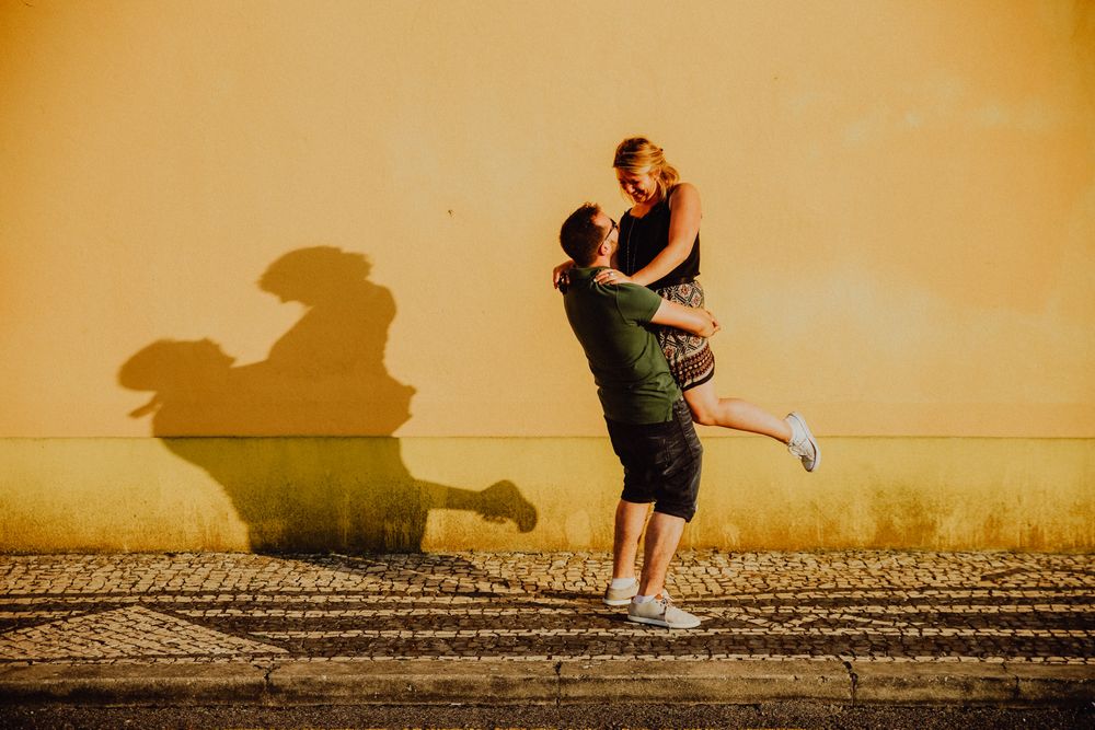Deux amoureux sautent devant un mur jaune