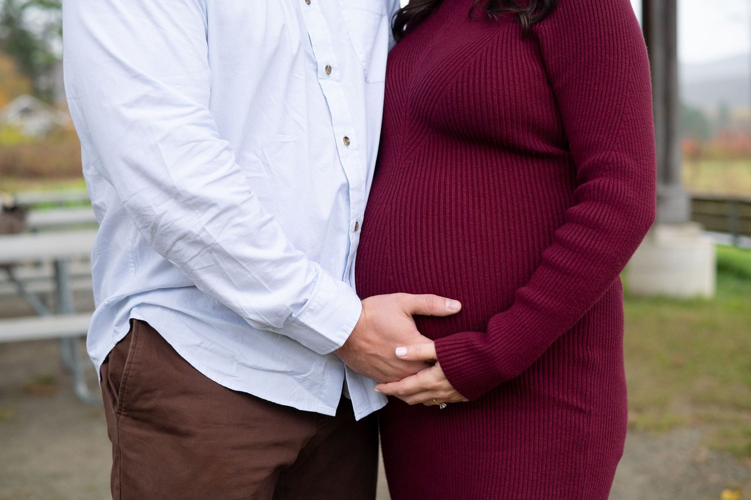 A dad cradles his partners baby bump in this maternity photo.