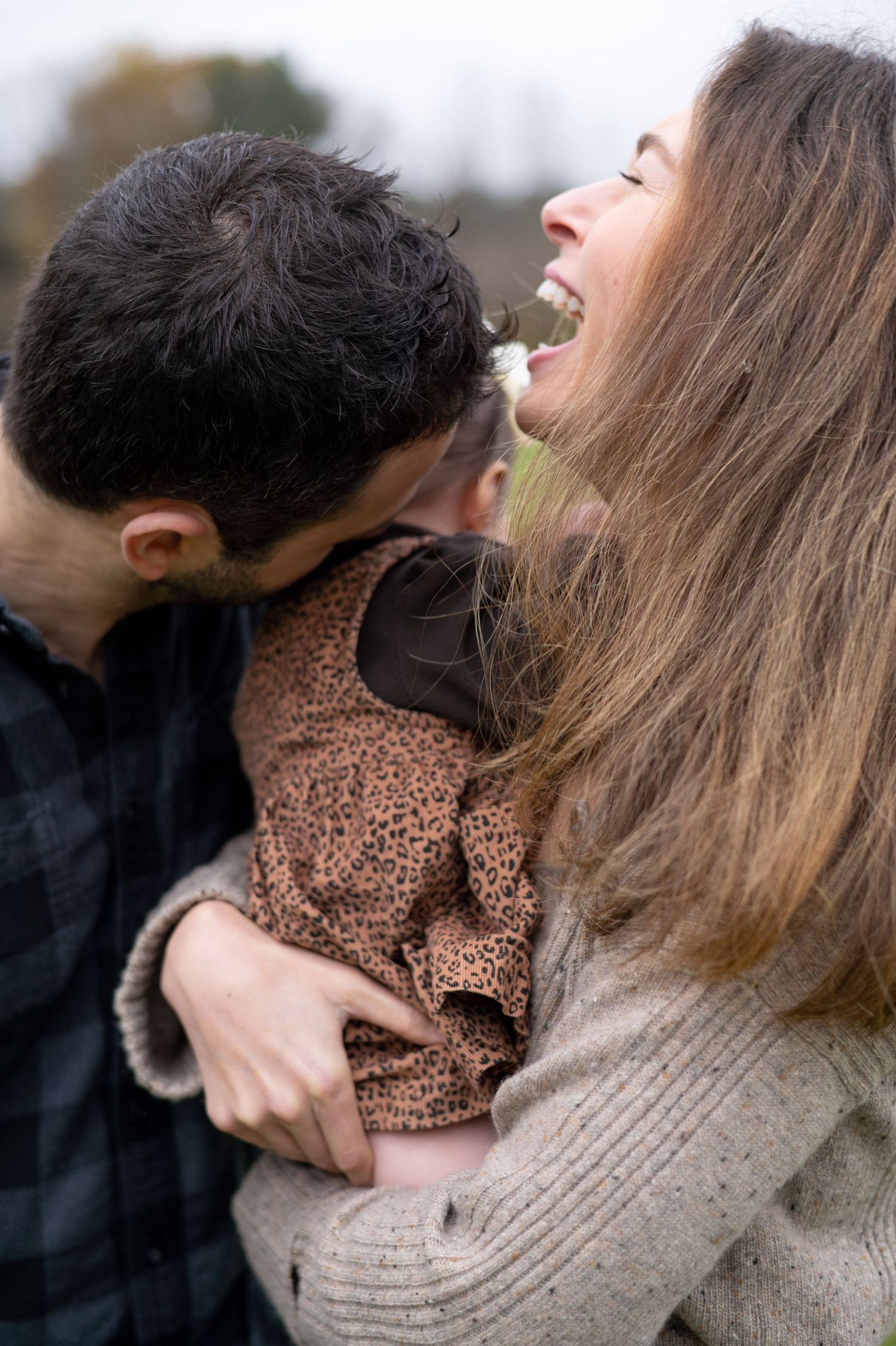 Parents laugh as they smother their baby girl in kisses