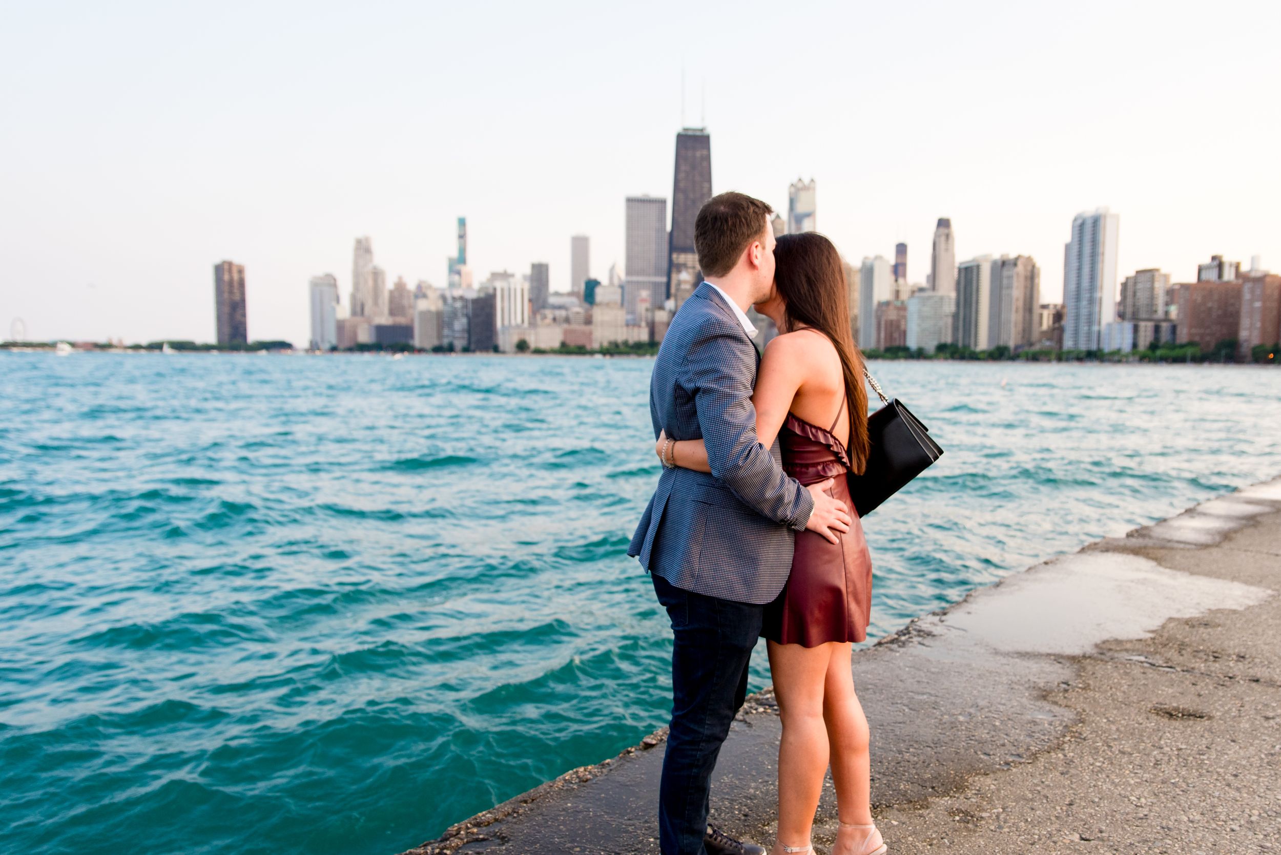 man and woman hugging after Chicago proposal at North Avenue Beach pier overlooking Lake Michigan