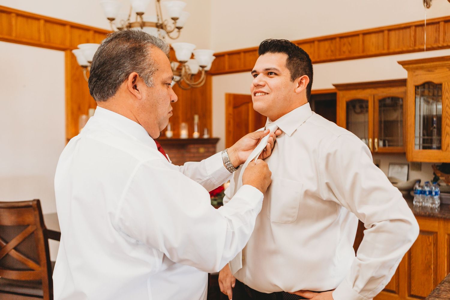 The father of the groom puts on the grooms tie during his Loveland Wedding.