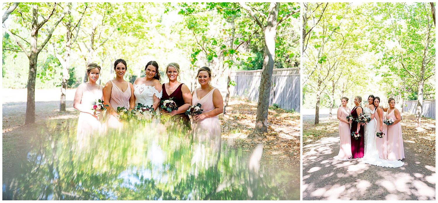 bride and bridesmaids smiling in a path of trees wearing blush and red for a September wedding in Northern California