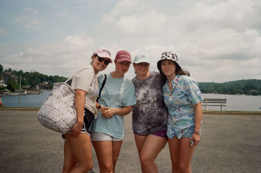 Group of friends posing together at a lake or marina on a summer day.