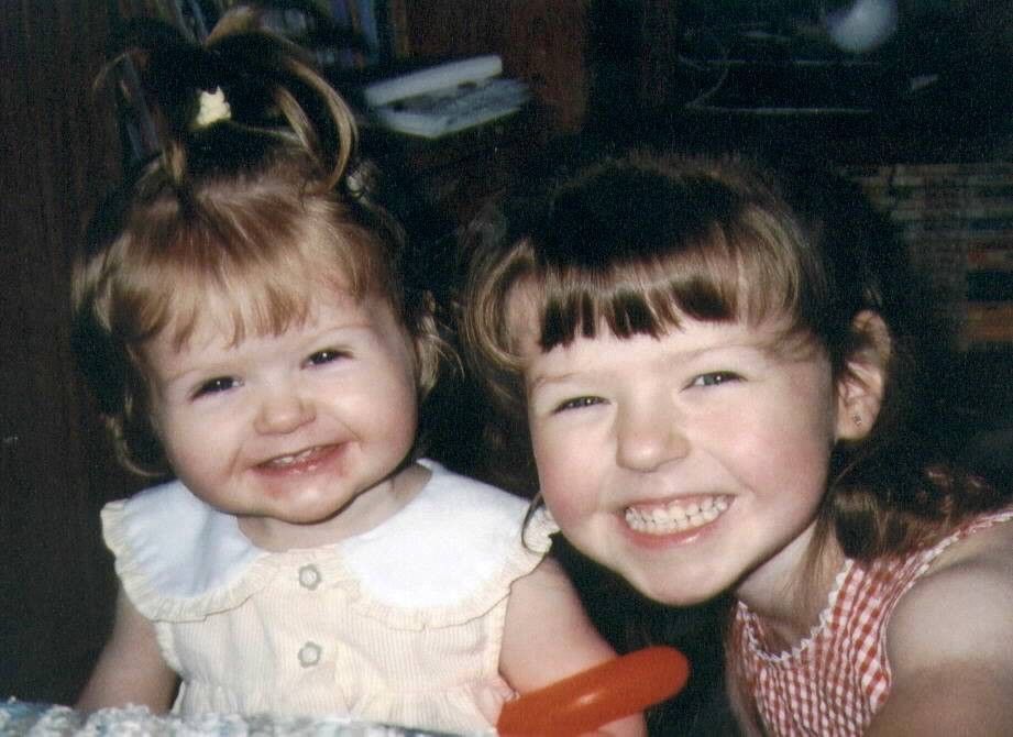 Two children smiling at camera in vintage-style photograph from the 1990s.
