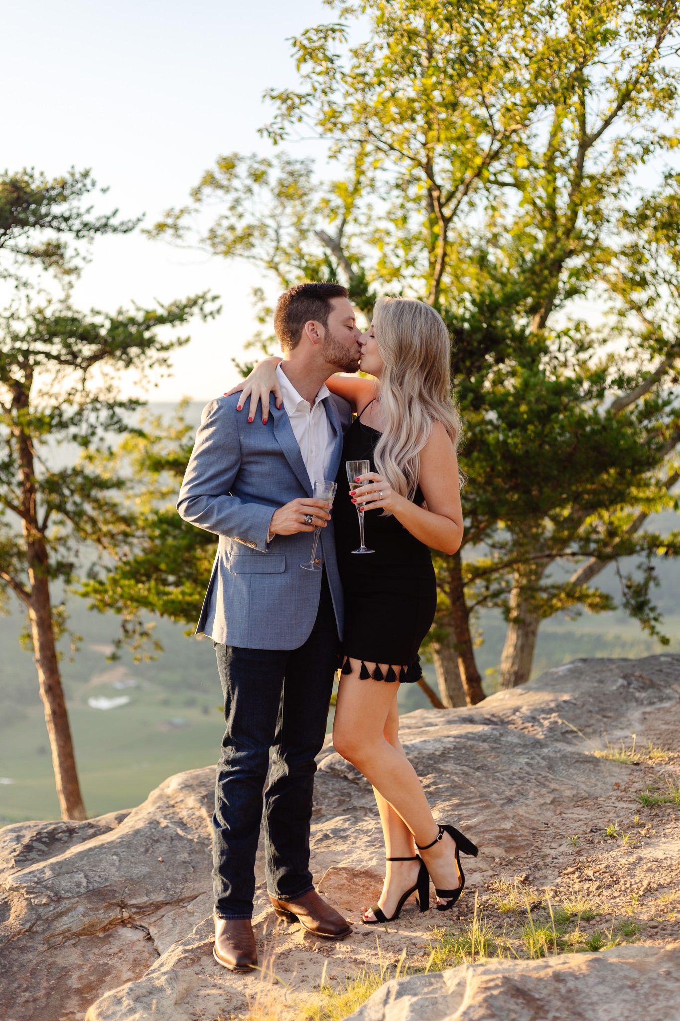 A couple kisses on top of a mountain after their surprise proposal captured by engagement photographer Sarah Swainson.