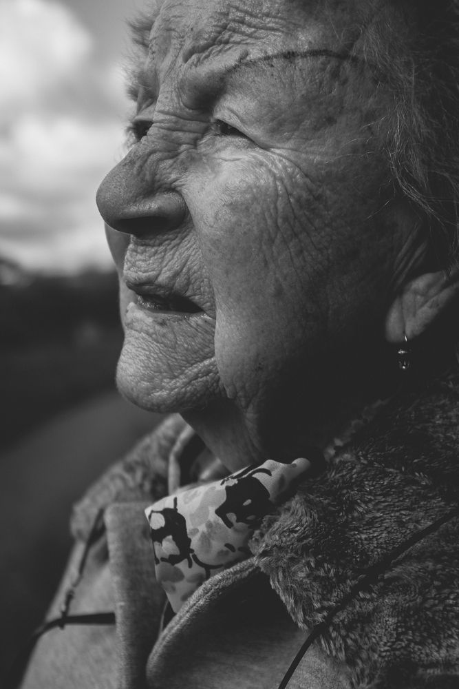Candid profile portrait showing joy and weathered features against cloudy sky.