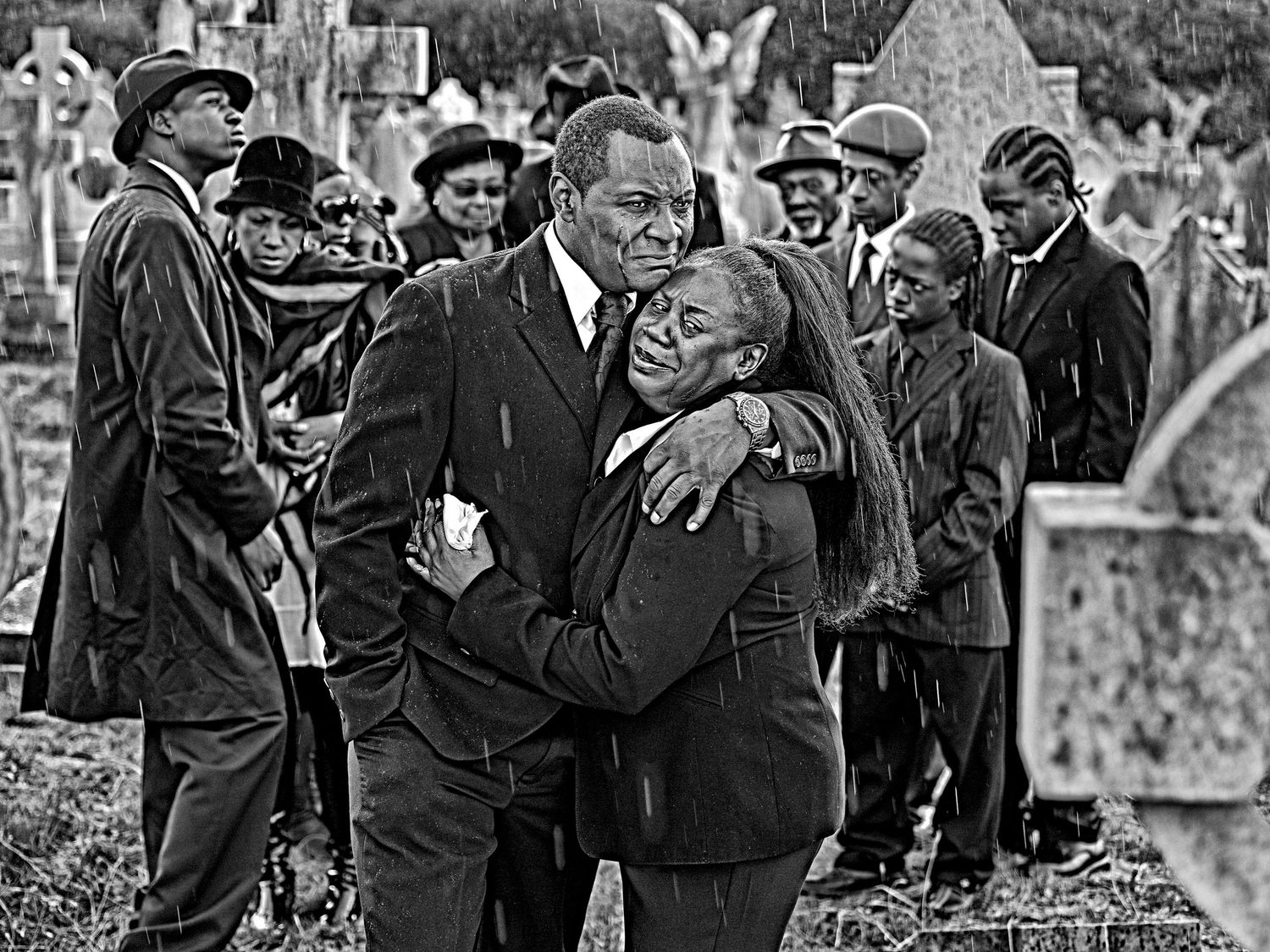 Historical black and white photo showing an emotional moment at a cemetery.