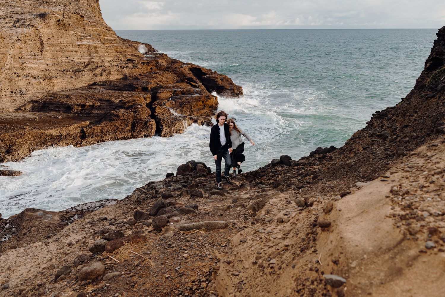 A couple hiking for their engagement shoot in Piha with Apertured Media-Auckland Wedding and Elopement Photographer
