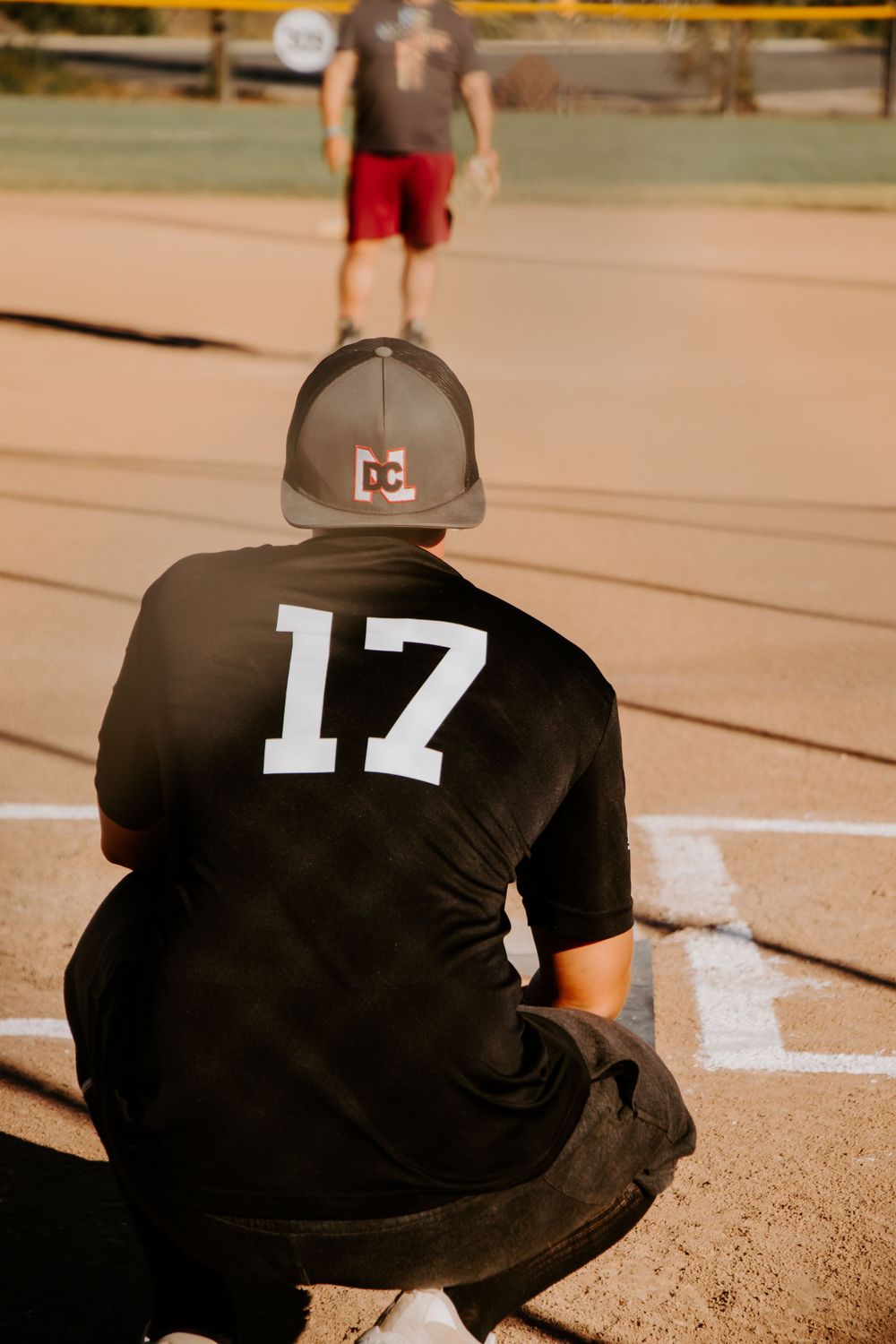 Baseball player wearing jersey number 17 crouches near home plate on dusty field.
