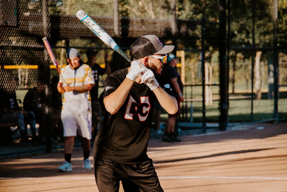 Baseball player in dark uniform at bat during afternoon game.