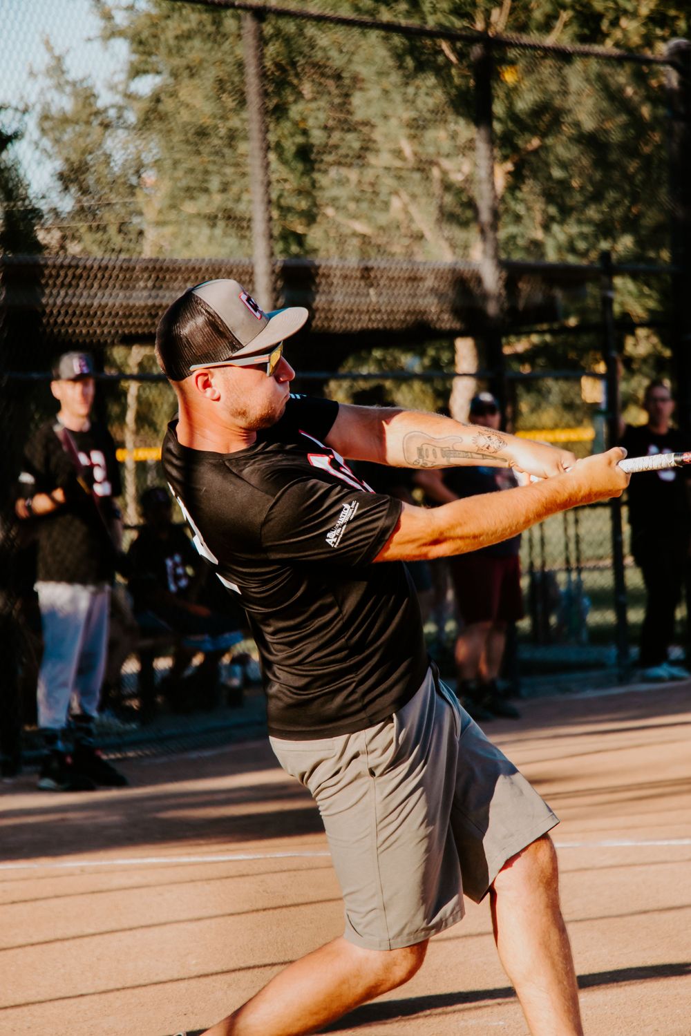 Player swinging baseball bat with intense focus during game on sunny field.