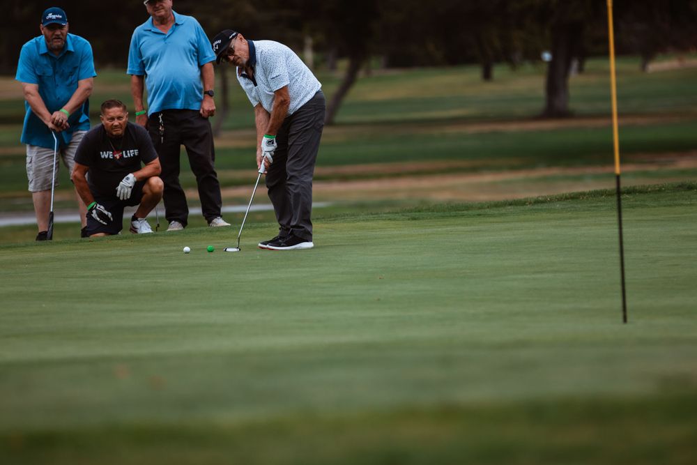 Golfers gather around the hole on putting green during late afternoon play.