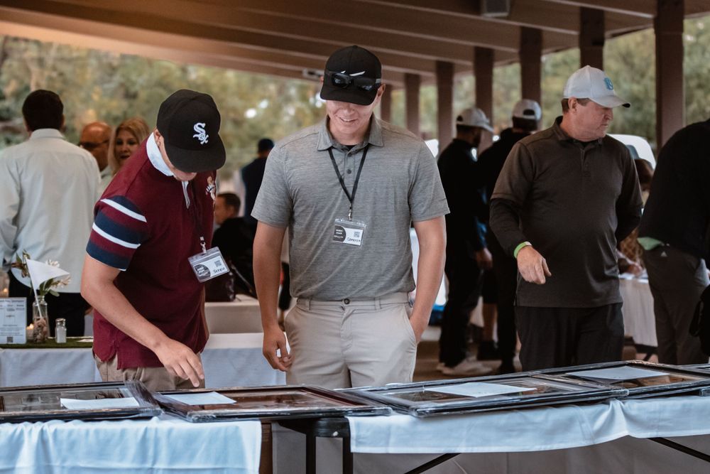 People review materials at registration table during outdoor event.