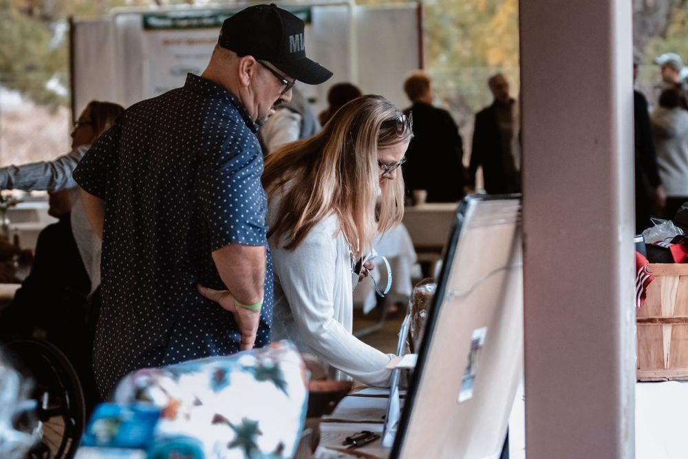 Attendees check in at registration desk during outdoor gathering.
