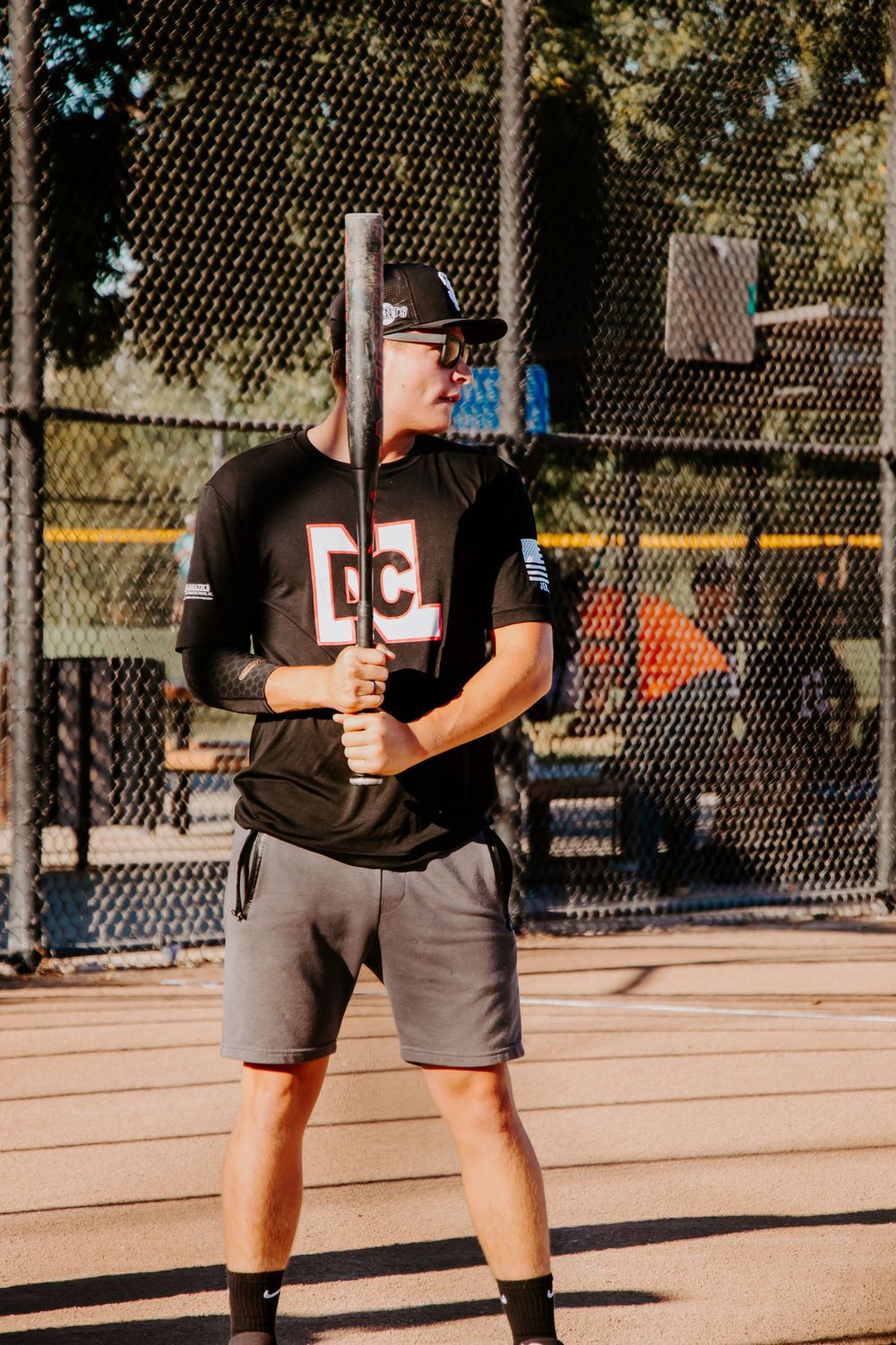 Baseball player in black uniform holds bat while preparing to hit.