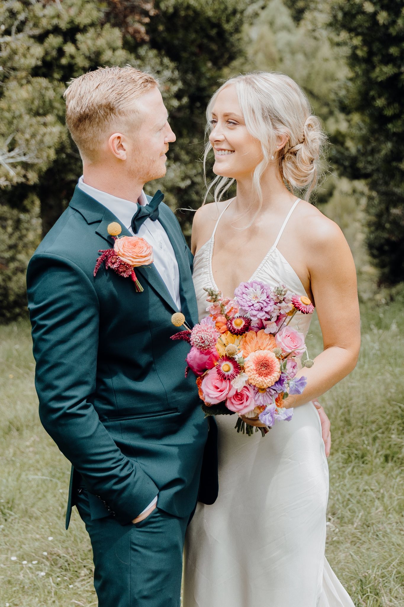 Wedding couple sharing intimate moment with vibrant floral bouquet.