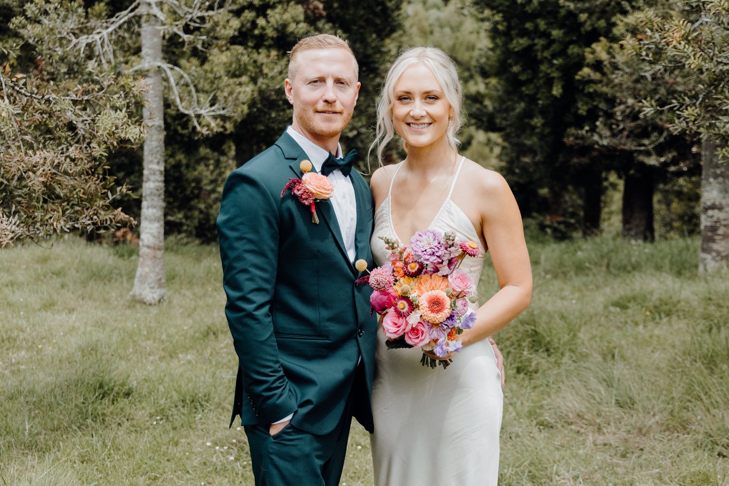 Wedding portrait in a forest setting with elegant floral bouquet.