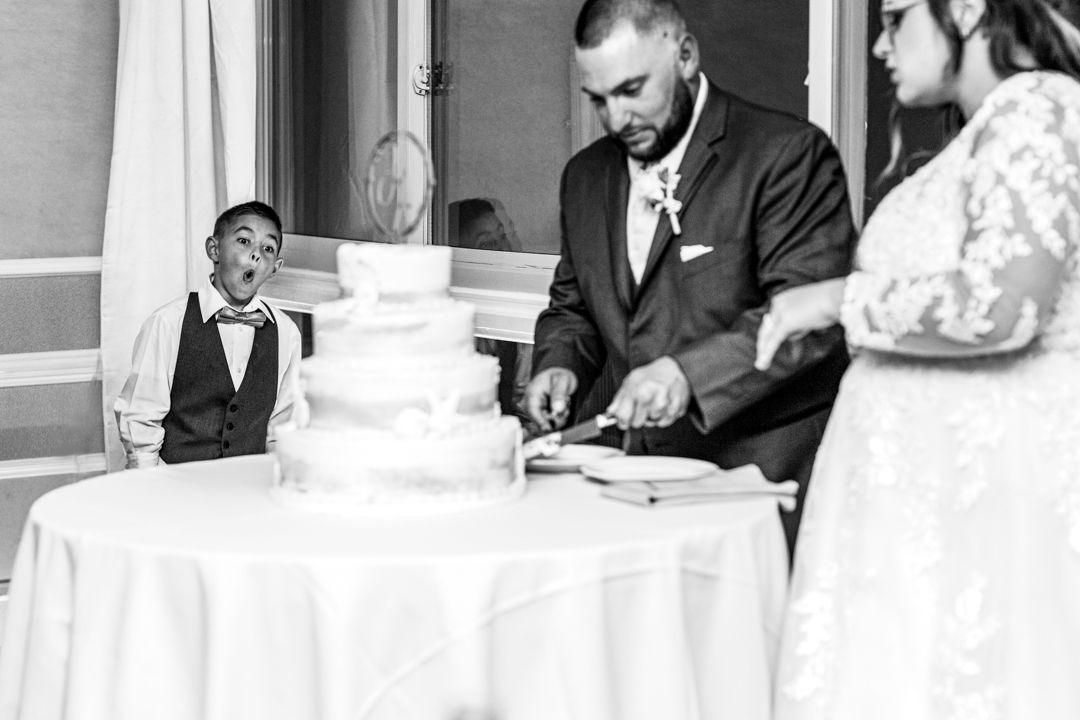 A wedding cake cutting moment captured in black and white at an indoor reception.