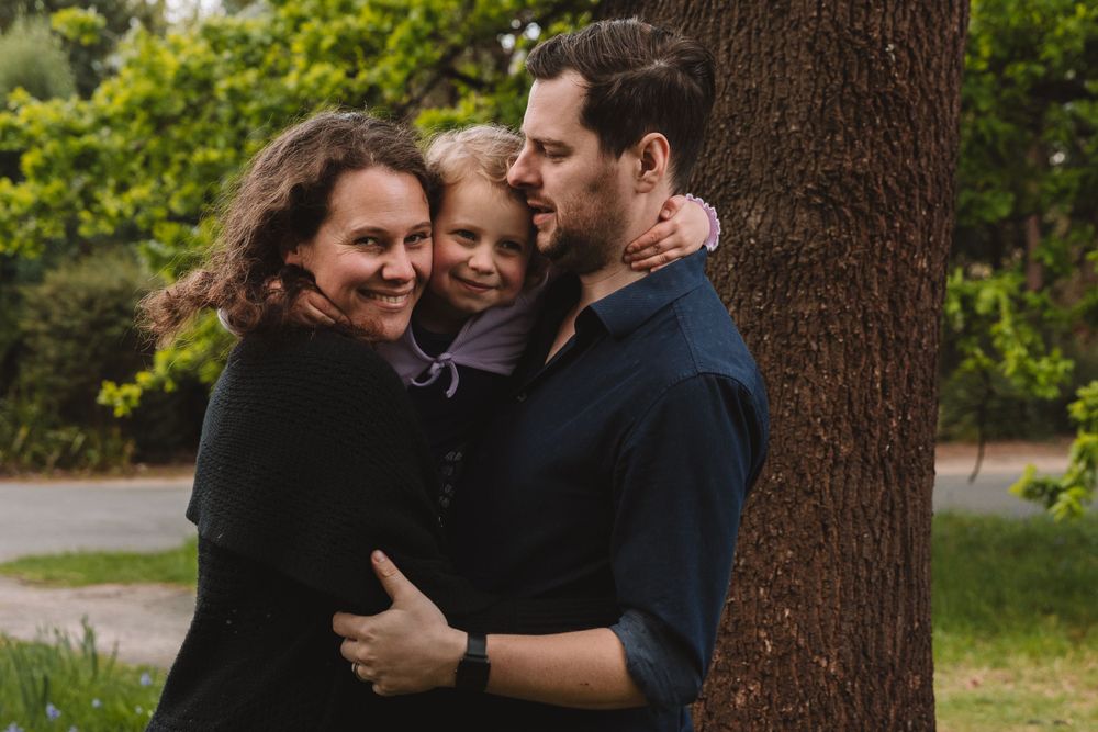 A sweet family moment captured outdoors with warm embraces and natural lighting.