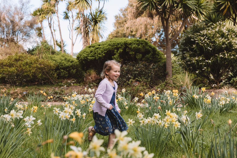 A young child runs joyfully through a field of blooming daffodils.