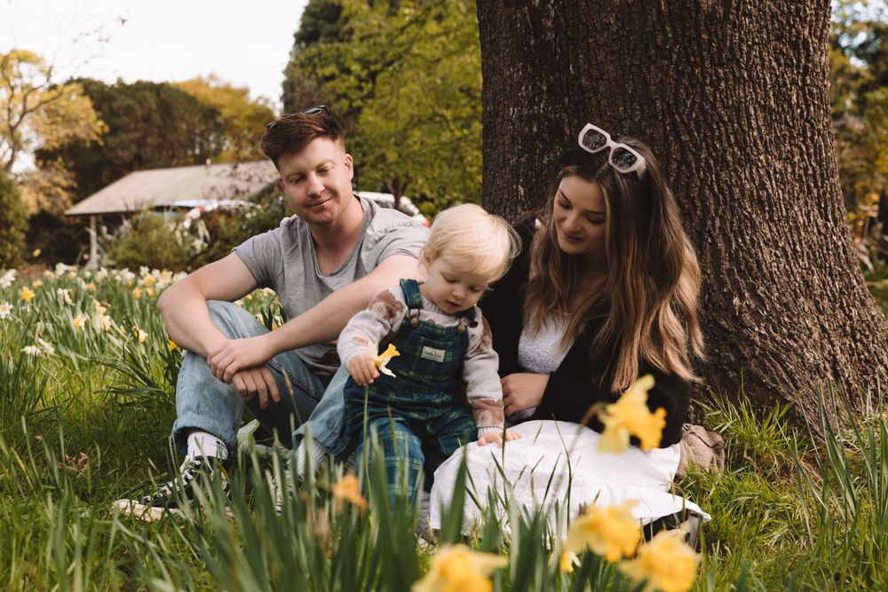A family sits together in a spring garden with blooming daffodils.