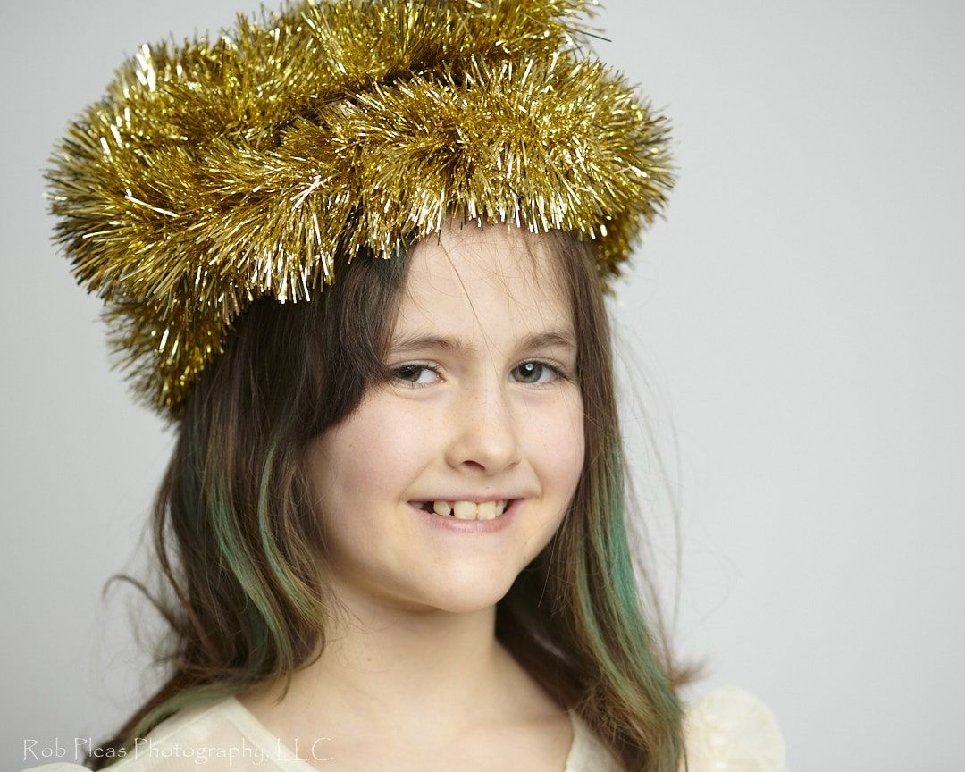 portrait of girl wearing headdress made of gold garland from the Christmas tree