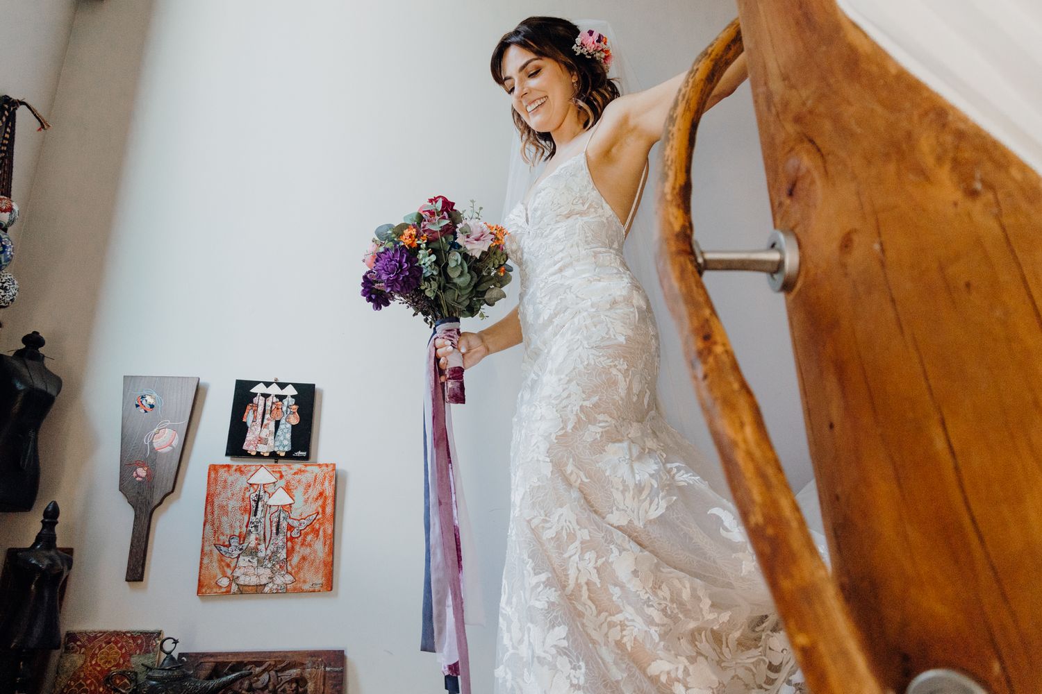A graceful pose on wooden stairs showcasing an intricate lace wedding gown.