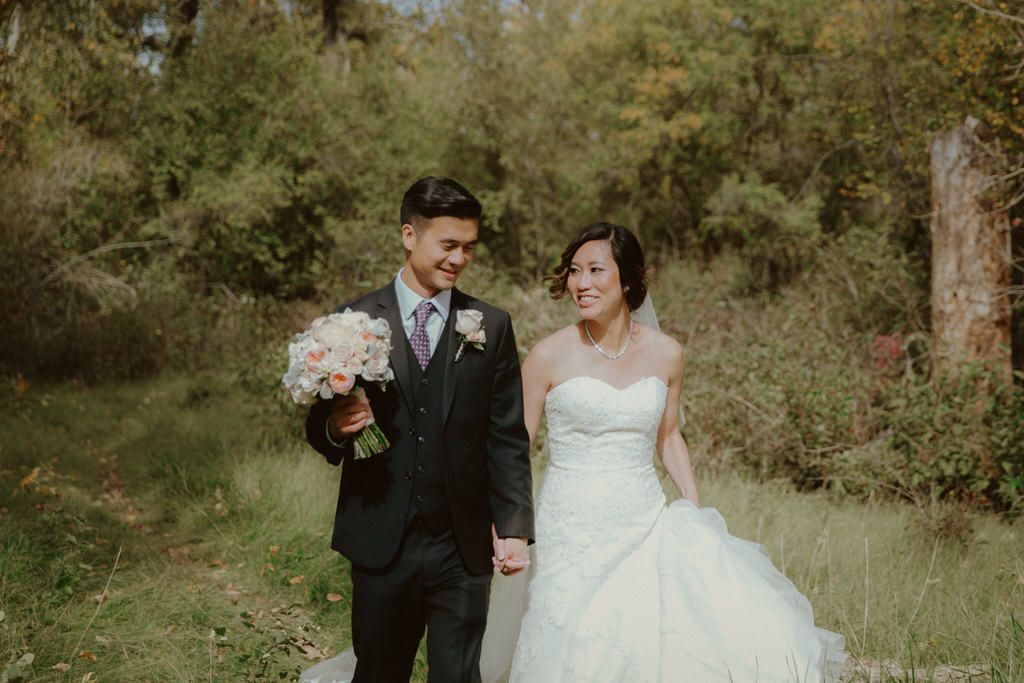 A couple poses in a lush outdoor garden setting during their wedding day.