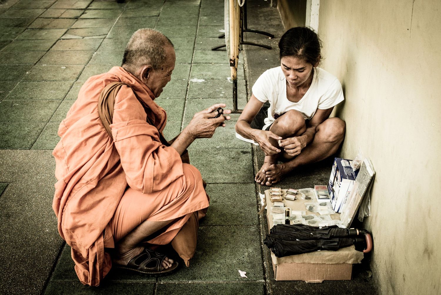 Monk looks at street sellers items on the streets of Bangkok Thailand