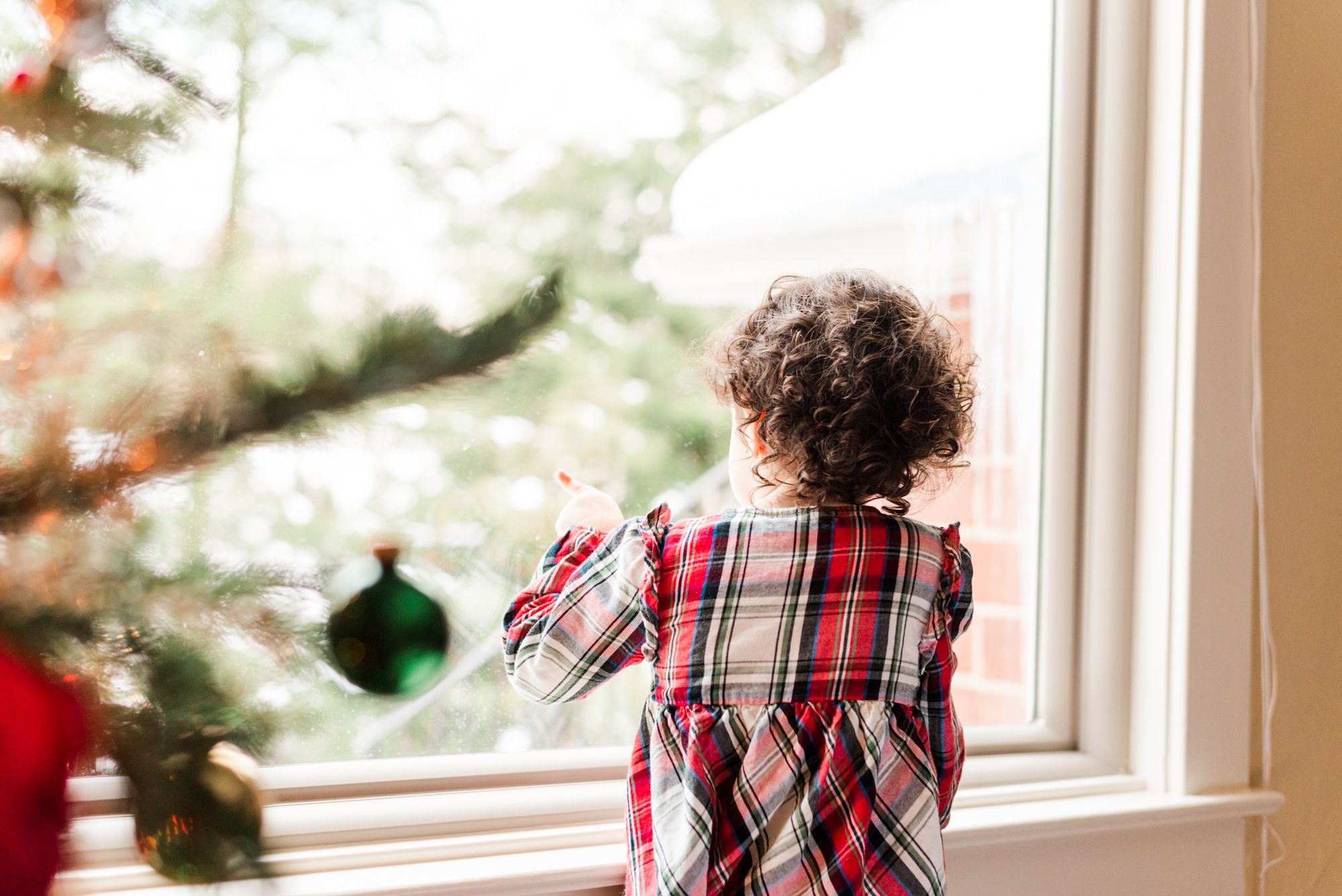 Big sister looking out the window in lifestyle newborn shoot