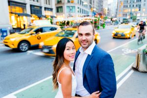 young engaged man and woman smiling at camera in front of yellow taxis in downtown Manhattan at sunset