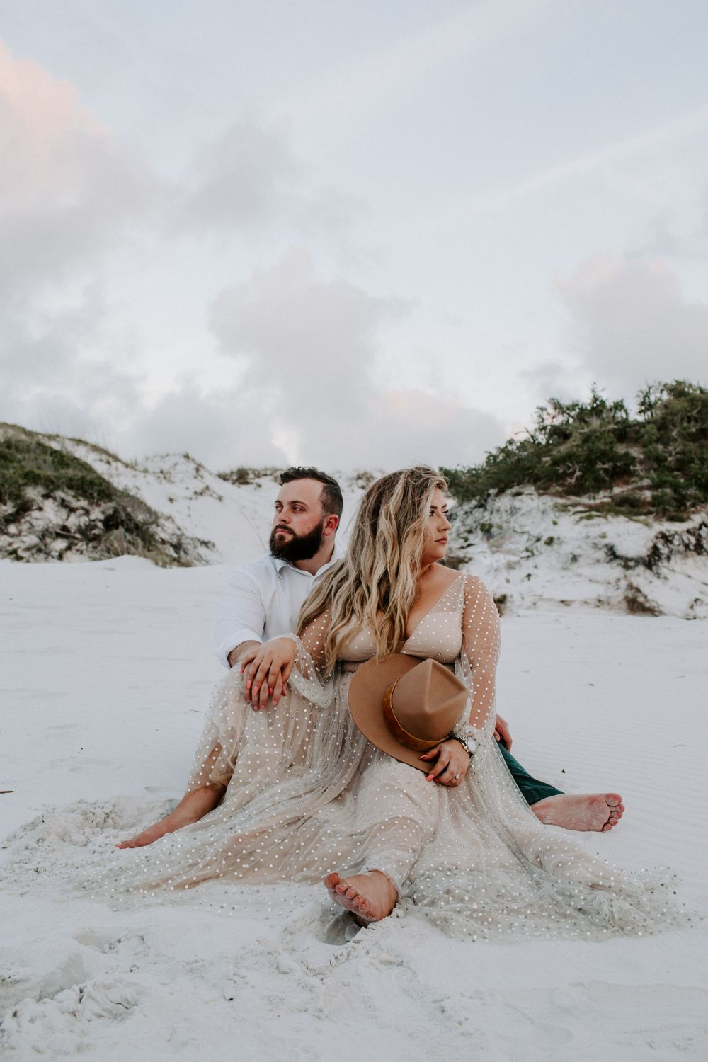 couple sitting on the sand dunes not looking at each other