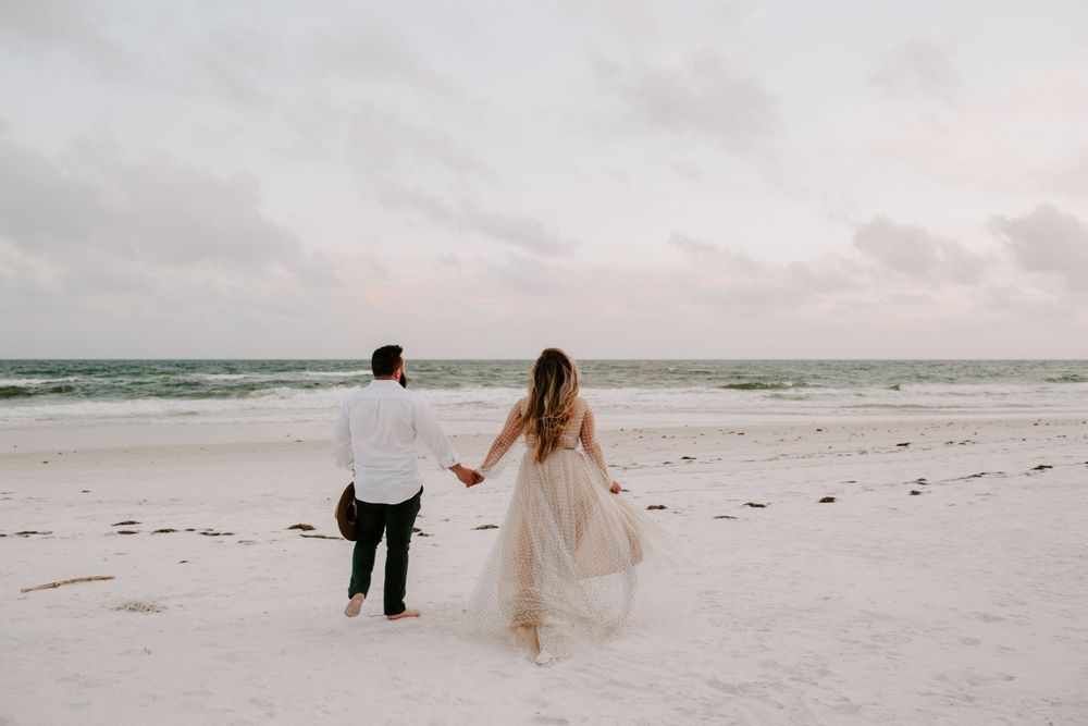 newly wed couple running towards the ocean