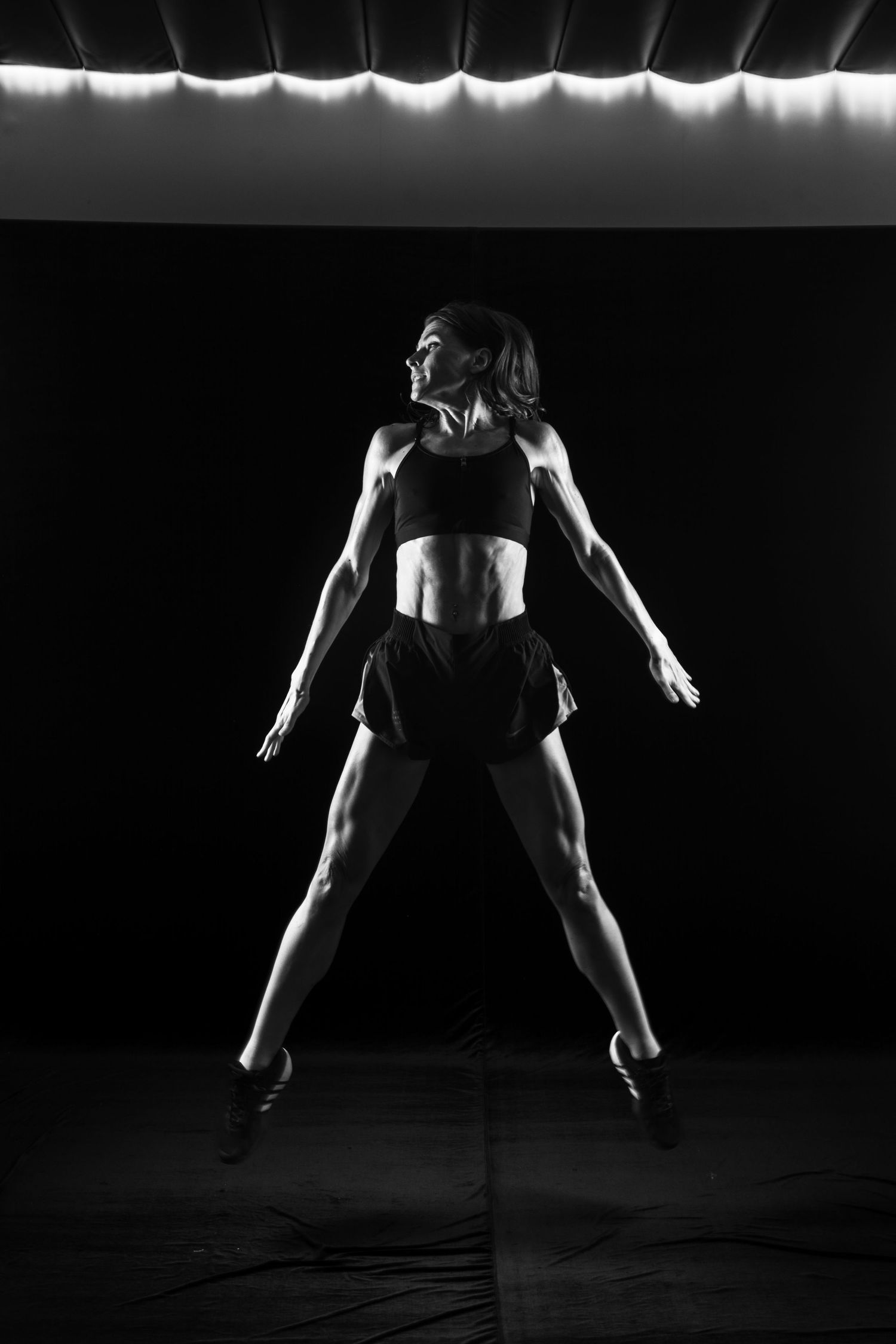 Low key photography of the athletic woman showing a muscular body. Taken by Anastasia Sokyrka based in Ho Chi Minh City
