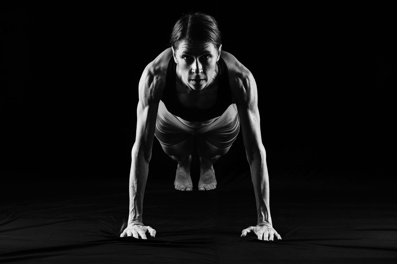 Low key photography of the athletic woman showing a muscular body. Taken by Anastasia Sokyrka based in Ho Chi Minh City