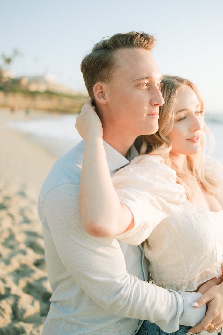 Couple in casual attire sharing an intimate moment on a sunny beach.