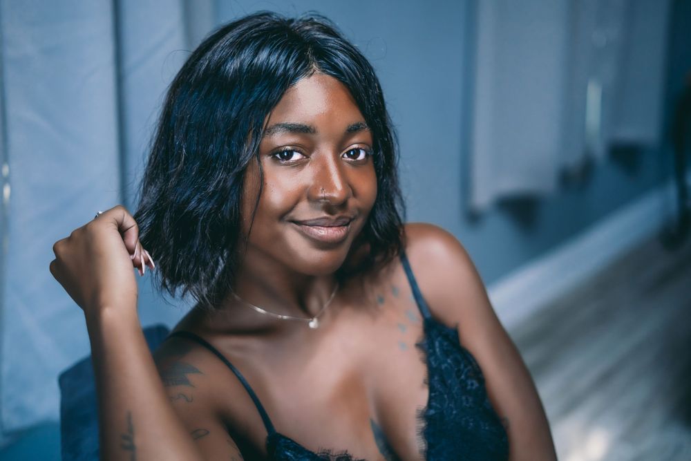 dark skinned woman in black bralette looking at the viewer and smiling
