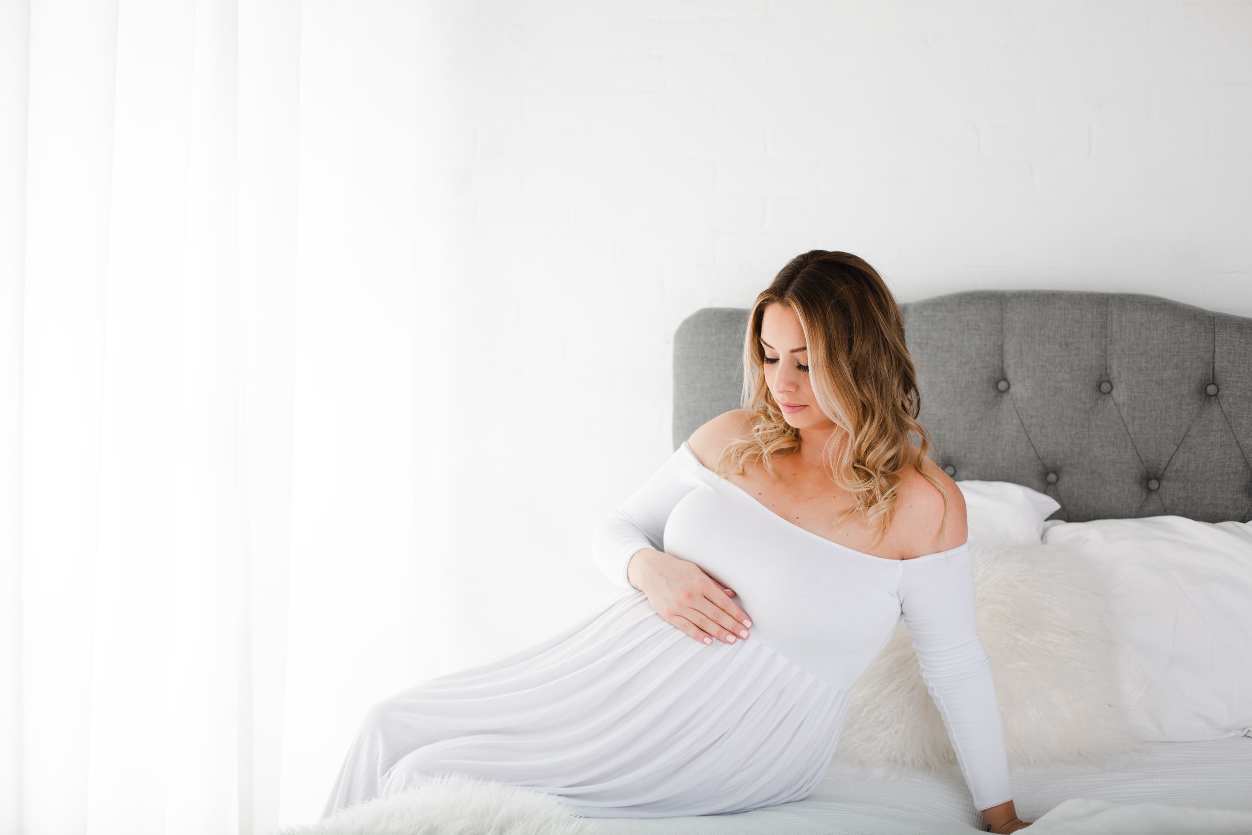 pregant lady sitting on bed posing - maternity session kelowna bc