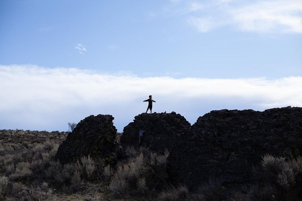 before image of boy standing on rock with outstretched arms