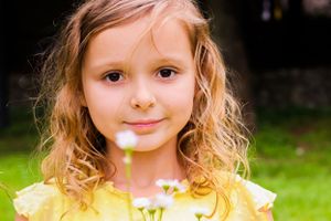 A bright and cheerful portrait in a yellow dress against a green outdoor background.