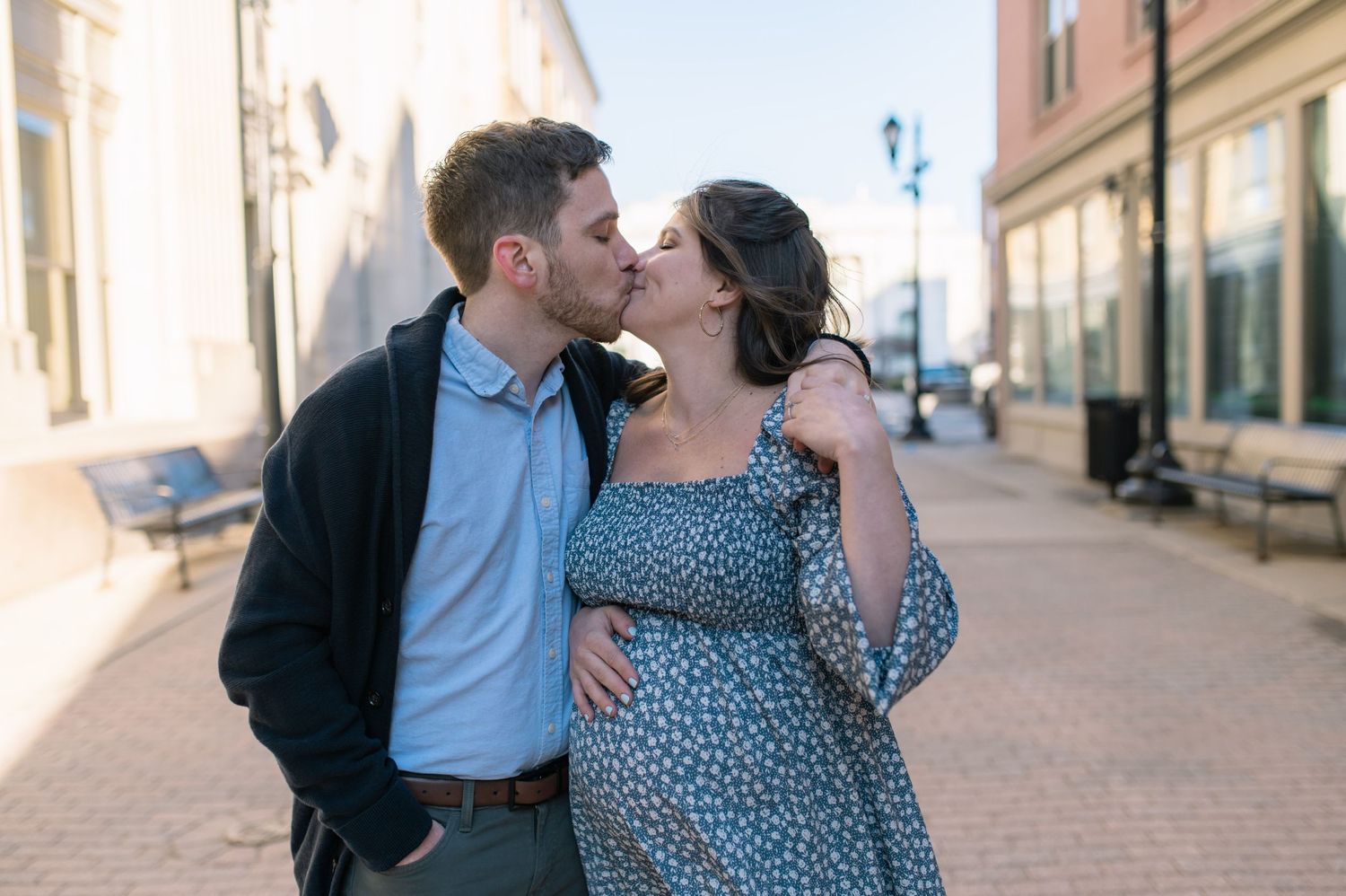 A romantic couple sharing an intimate moment on a sunlit urban street.